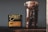A clear glass jar filled with roasted coffee beans is placed next to a black package of Onyx Coffee Lab's Ethiopia Agaro Family coffee. The package contains detailed information about the coffee, including its origin and flavor notes. The background is a plain, gray wall, and the items are positioned on a dark wooden surface.