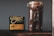 A clear glass jar filled with roasted coffee beans is placed next to a black package of Onyx Coffee Lab's Ethiopia Agaro Family coffee. The package contains detailed information about the coffee, including its origin and flavor notes. The background is a plain, gray wall, and the items are positioned on a dark wooden surface.