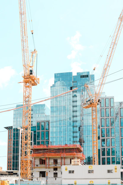 A construction site showing a modern urban transformation project in progress with cranes and workers.