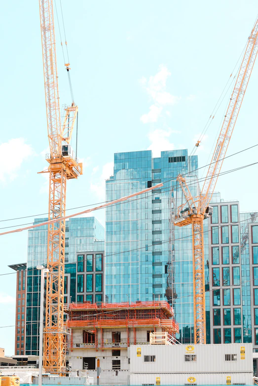 A modern construction site with cranes and workers actively building a high-rise structure in Singapore.
