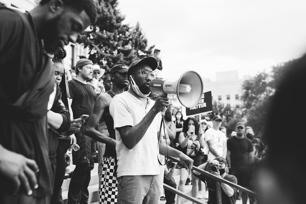 grayscale photo of man in white crew neck t-shirt holding microphone