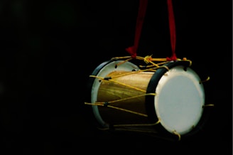 white and brown drum with red strap
