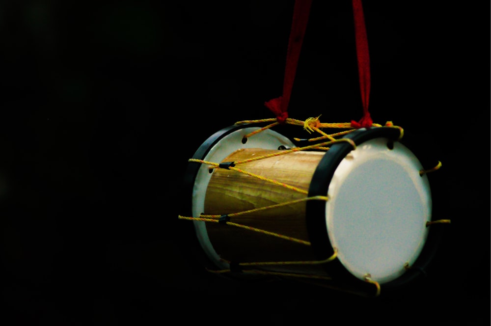 white and brown drum with red strap