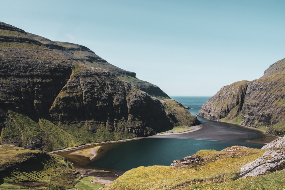 green and brown mountain beside river during daytime