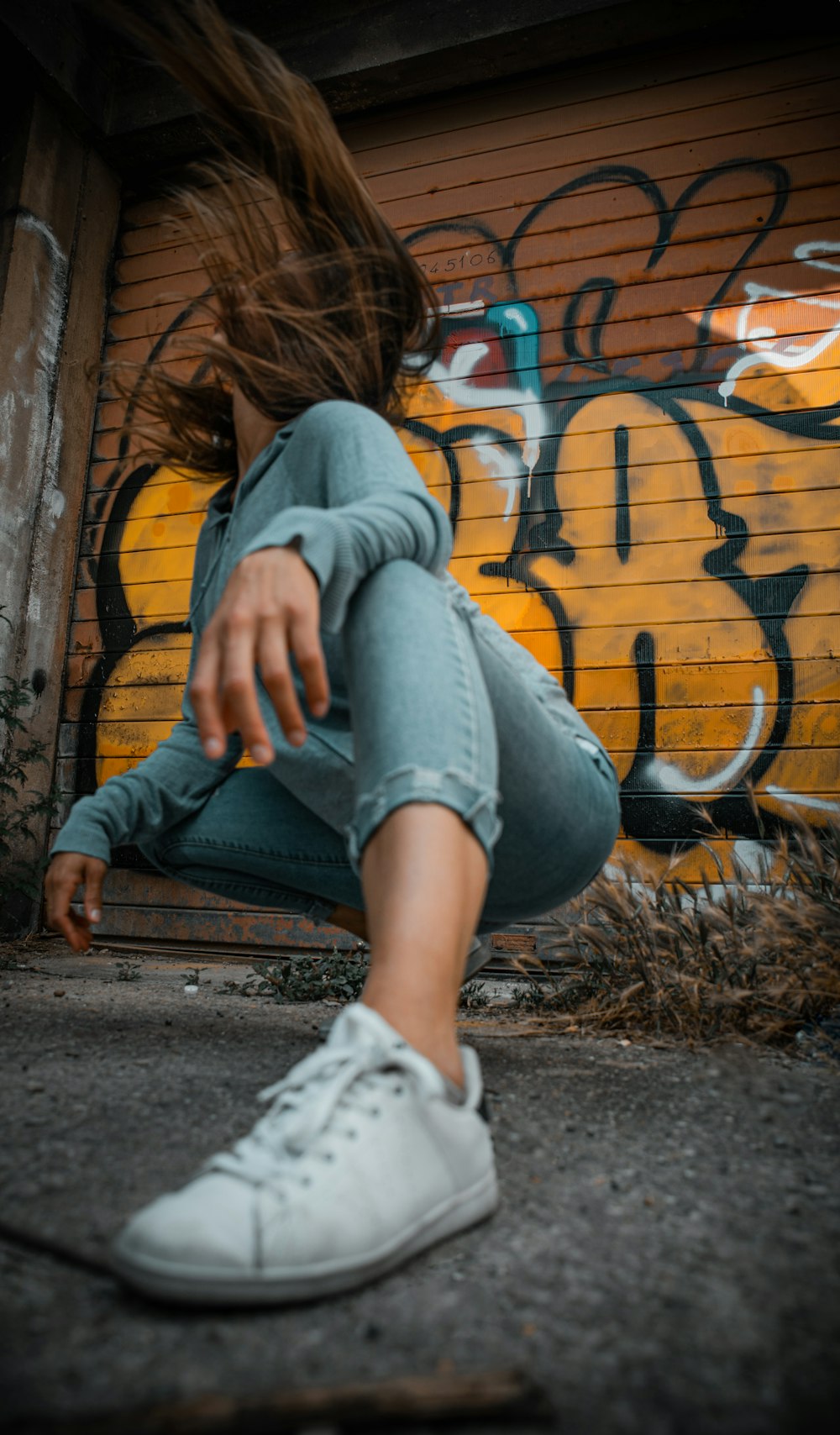 woman in gray hoodie and blue denim jeans sitting on brown wooden bench