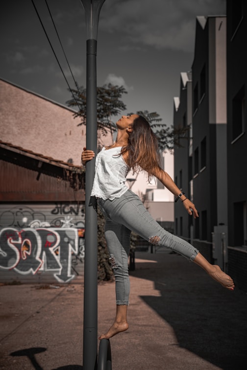 woman in white long sleeve shirt and gray pants standing on gray concrete road during daytime