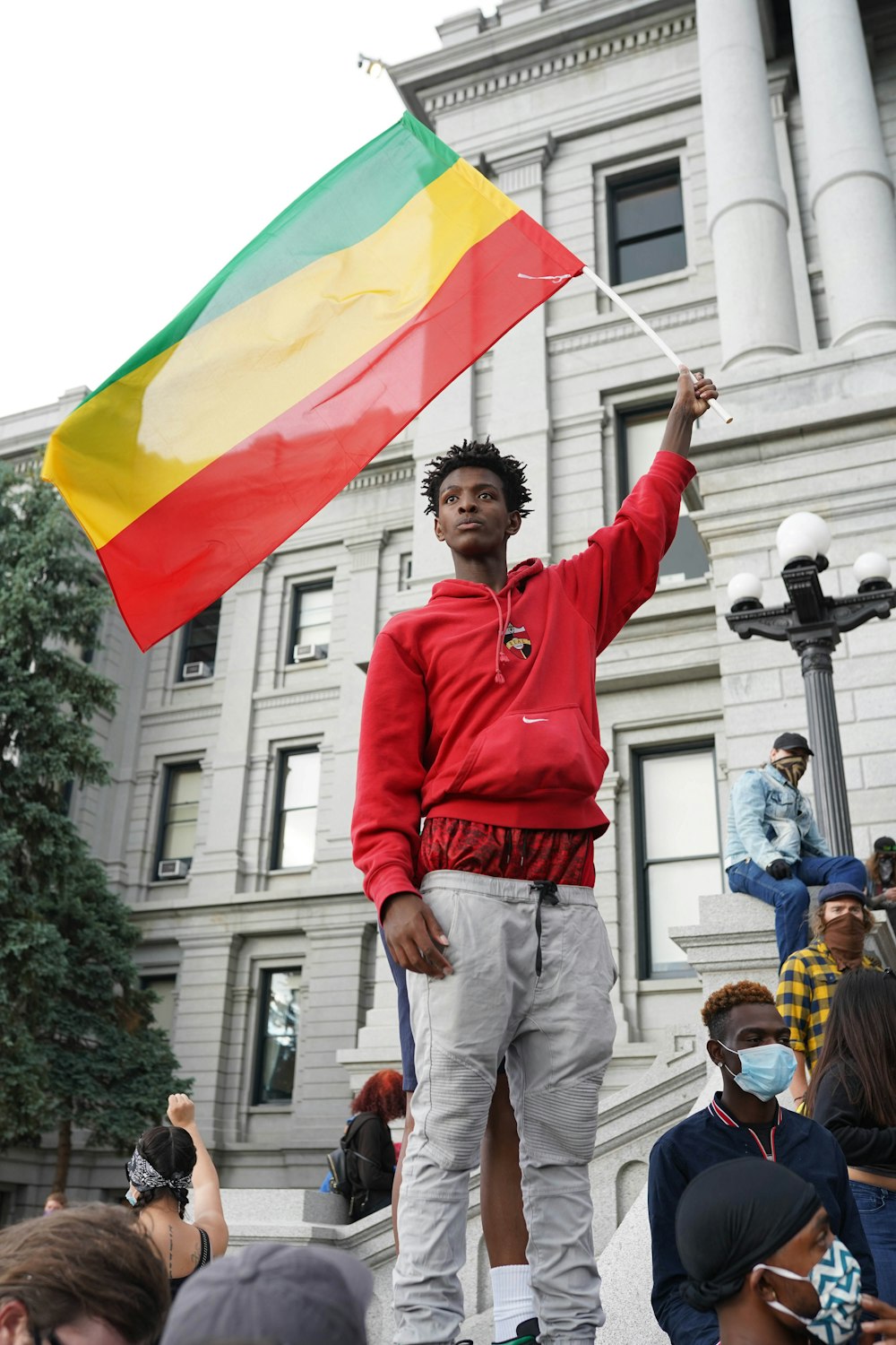 man in red long sleeve shirt holding yellow and red flag