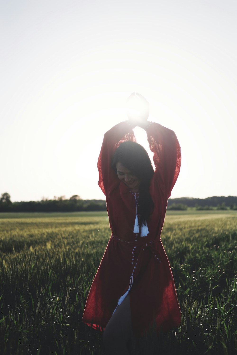 woman in red dress standing on green grass field during daytime