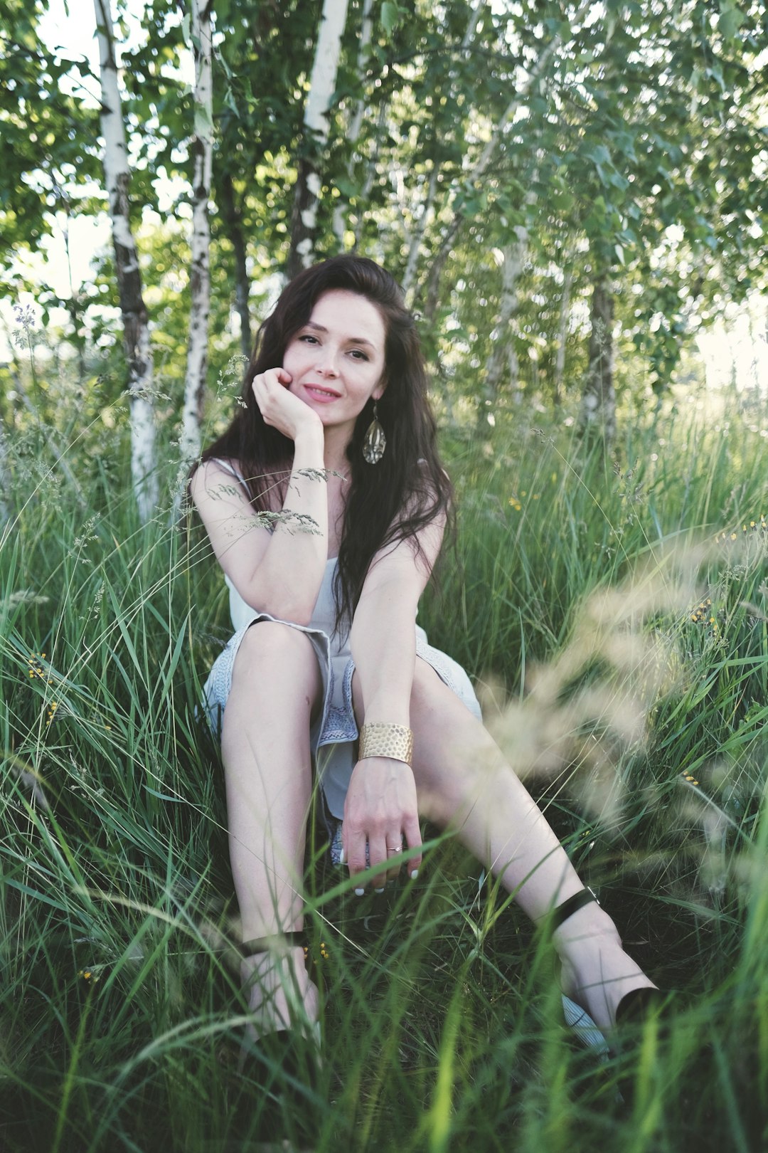 woman in white brassiere and blue denim shorts sitting on green grass field