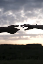 A symbolic handshake bridging two different political symbols against a backdrop of a sunrise.