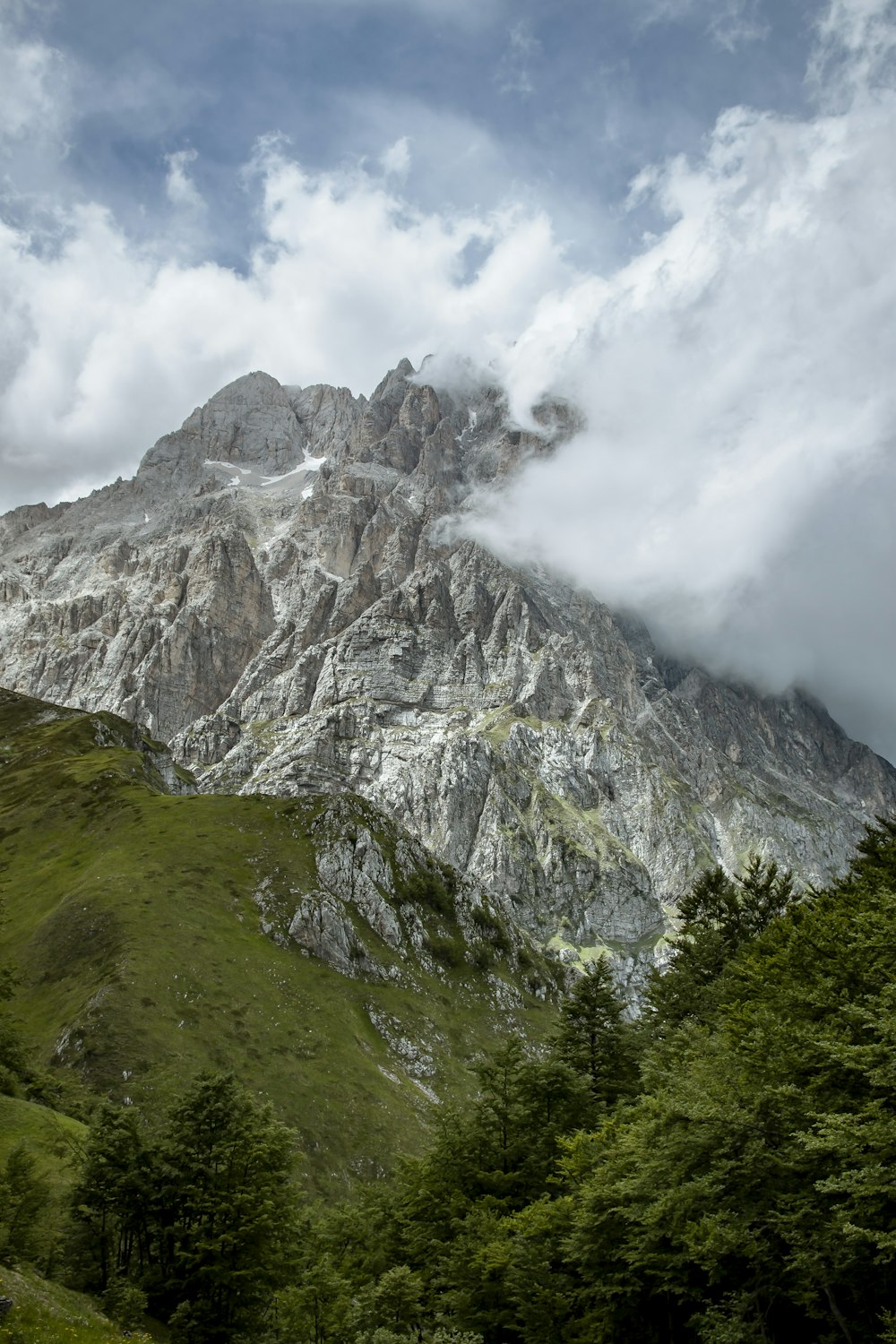 montaña verde y gris bajo nubes blancas durante el día