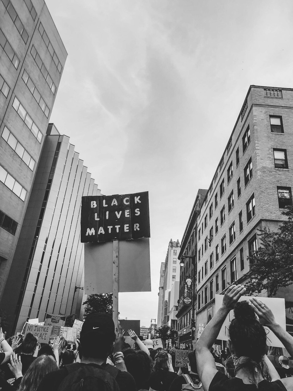 grayscale photo of man in black jacket and black pants walking on pedestrian lane