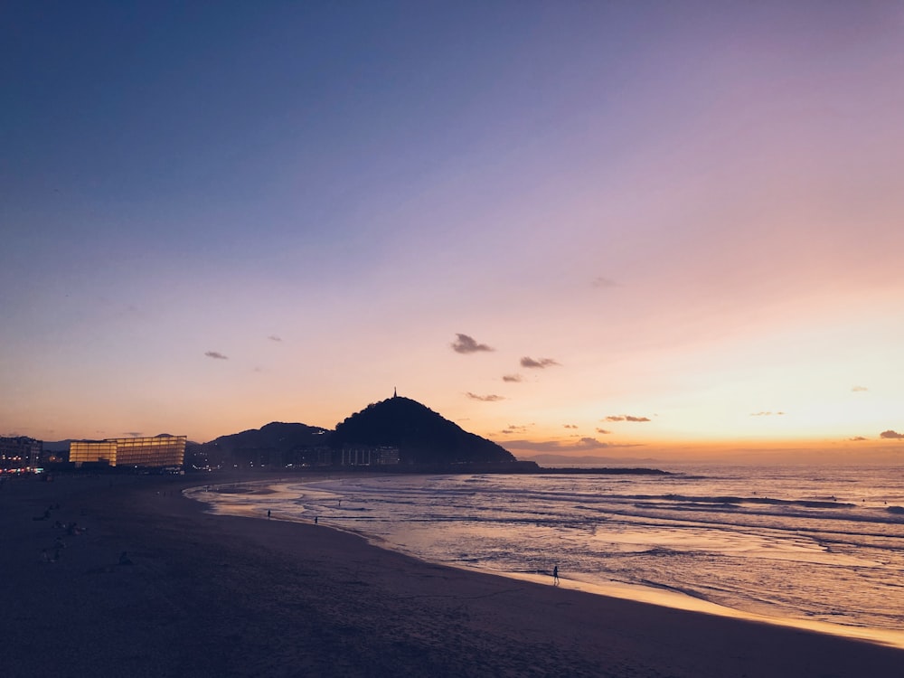 silhouette of building near sea during sunset