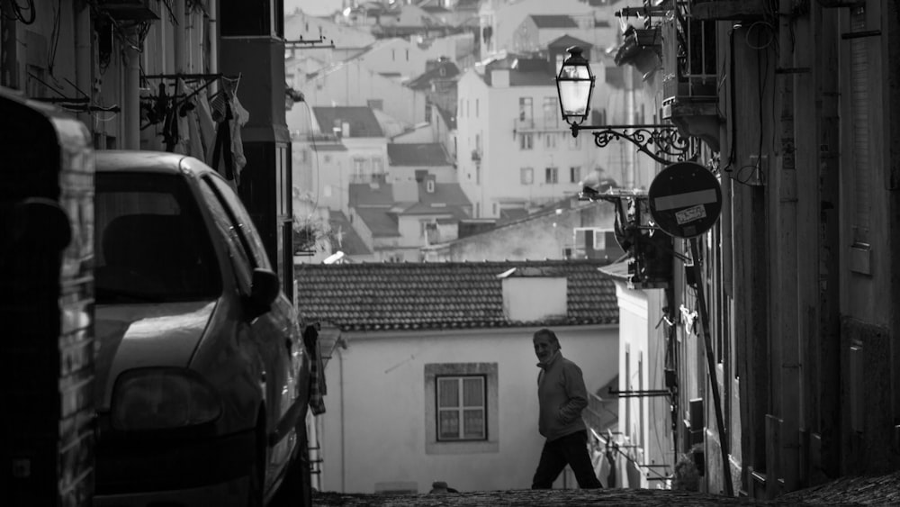 Photo en niveaux de gris d’un homme en veste noire debout près d’une voiture