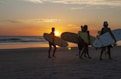 2 men holding surfboard walking on beach during sunset