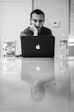grayscale photo of macbook air beside clear plastic bottle