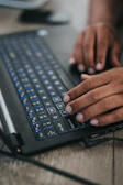 Hands typing on a laptop keyboard with blue and orange accents in the background