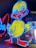 A brightly illuminated neon sign of a cartoon-style duck. The duck is outlined in vibrant blue with a yellow body and red beak. It stands in front of other neon signs, which include partially visible letters in red and blue.