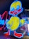 A brightly illuminated neon sign of a cartoon-style duck. The duck is outlined in vibrant blue with a yellow body and red beak. It stands in front of other neon signs, which include partially visible letters in red and blue.