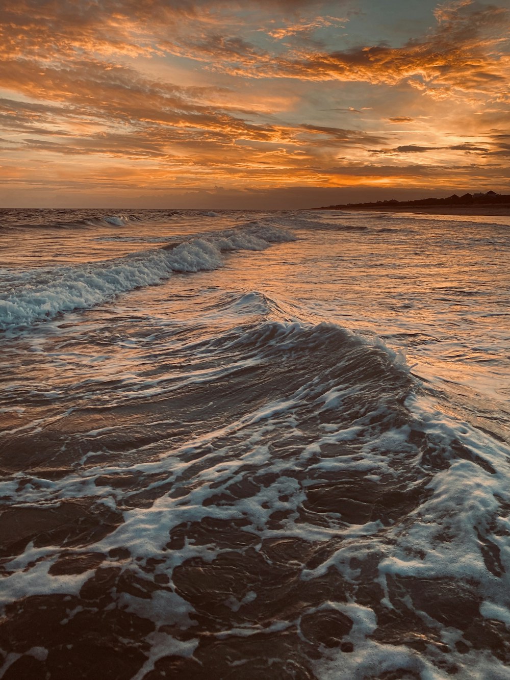 ocean waves crashing on shore during sunset