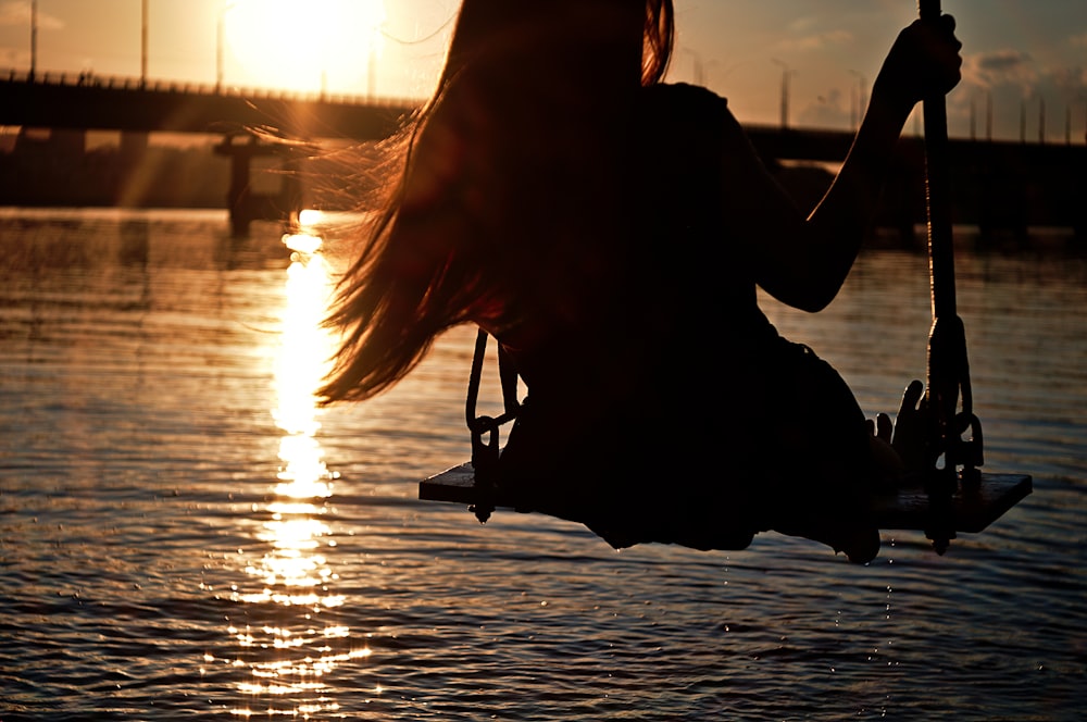 woman sitting on chair on beach during sunset