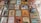 A collection of colorful greeting cards displayed on a wooden surface. The images range from illustrated faces and patterns to birthday messages with playful and humorous designs. Some cards feature people in various poses, while others have drawings like a cactus, a giraffe, and modern art-style illustrations.