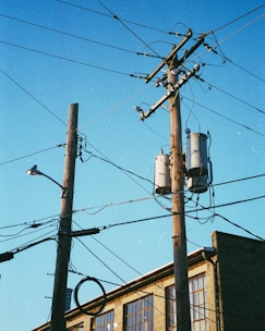 gray electric post under blue sky during daytime