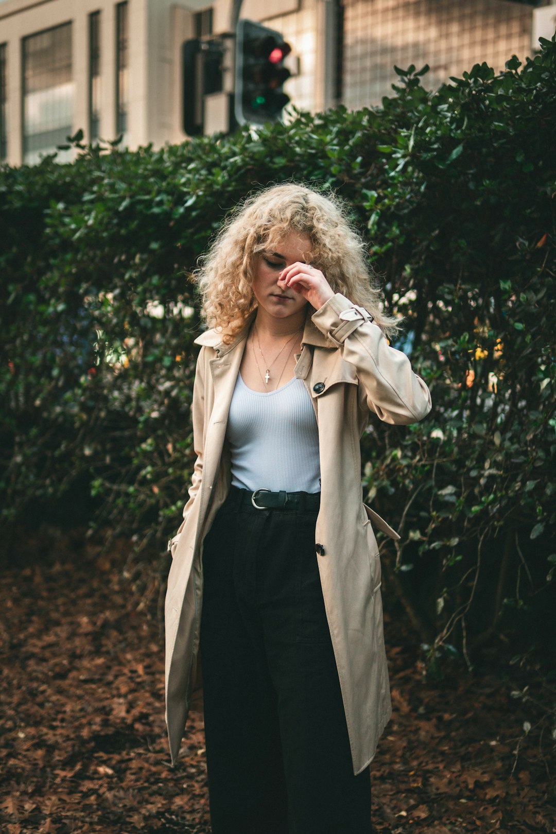 woman in brown coat standing near green plants during daytime