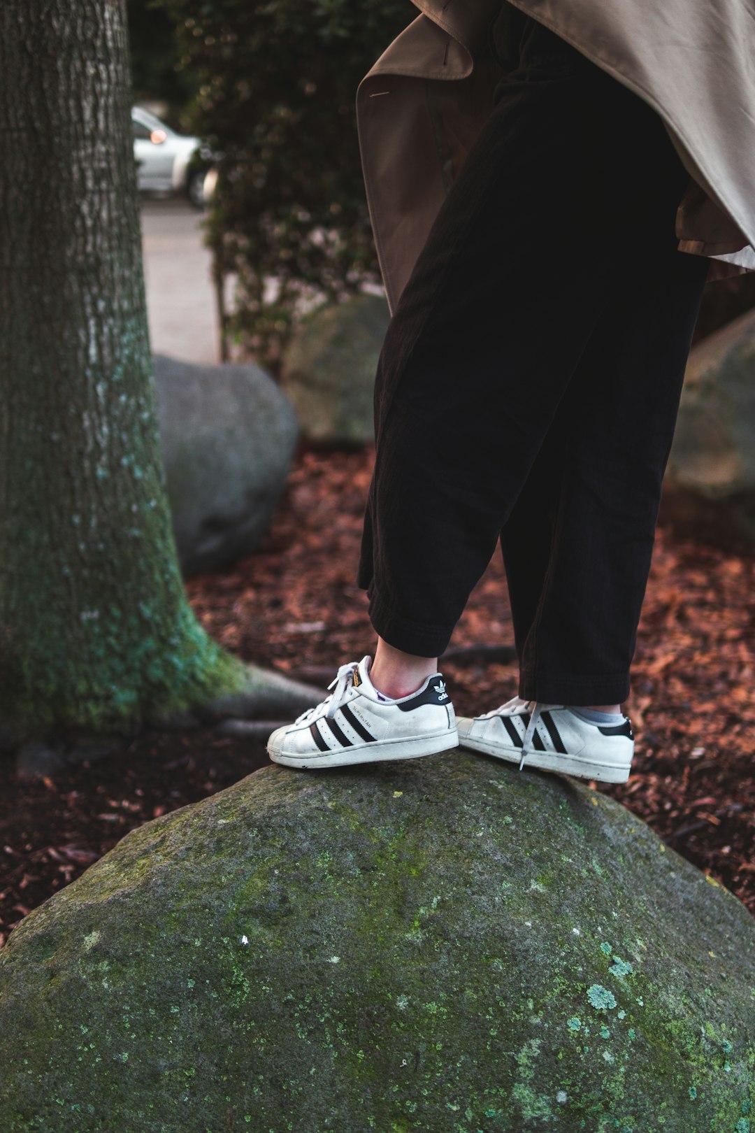 person in black pants and white and black adidas sneakers