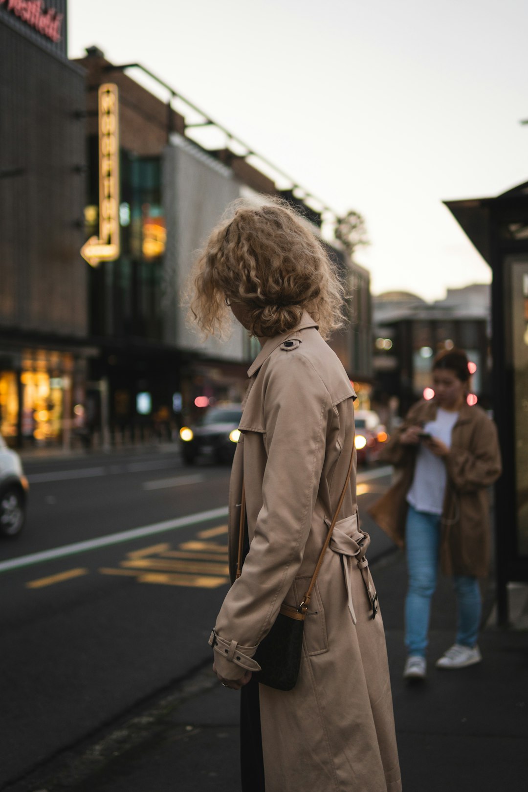 woman in brown coat standing on the street during daytime