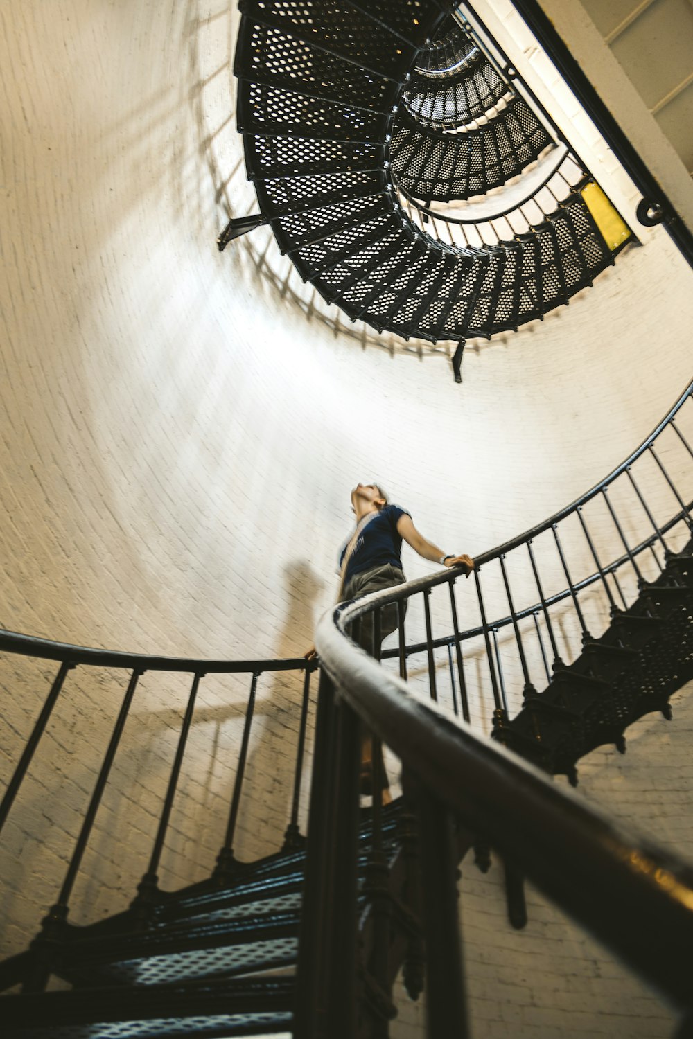woman in blue jacket walking down on spiral staircase