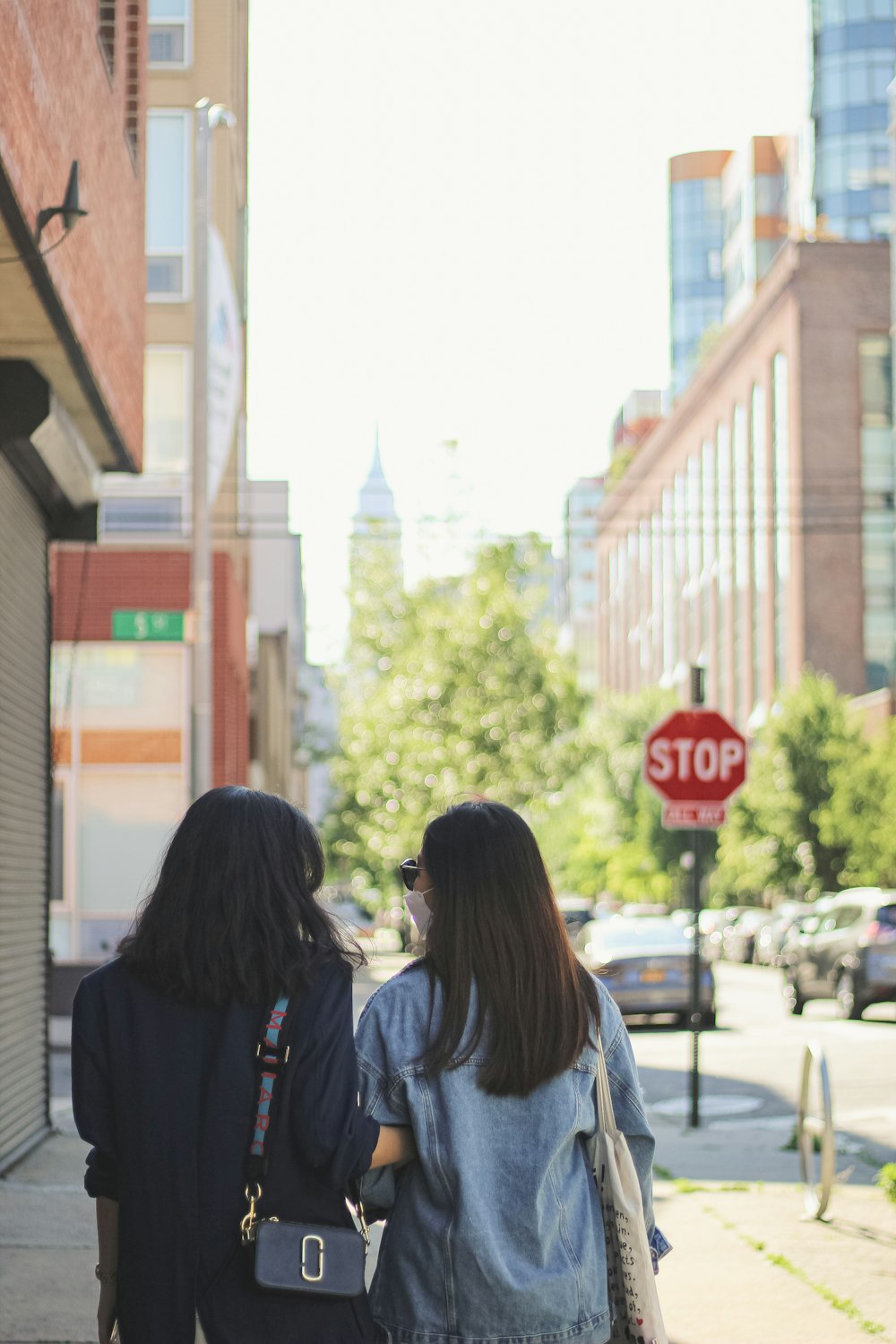 2 mujeres caminando por la acera durante el día