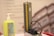 A sphygmomanometer and a pump bottle are placed on a light-colored surface. The sphygmomanometer has a gauge with clearly marked increments and a rubber tube attached to it. The background features a blurry image of a building.