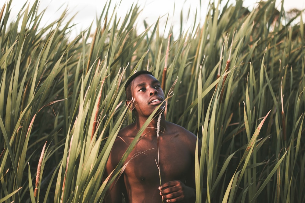 topless man standing near green grass during daytime