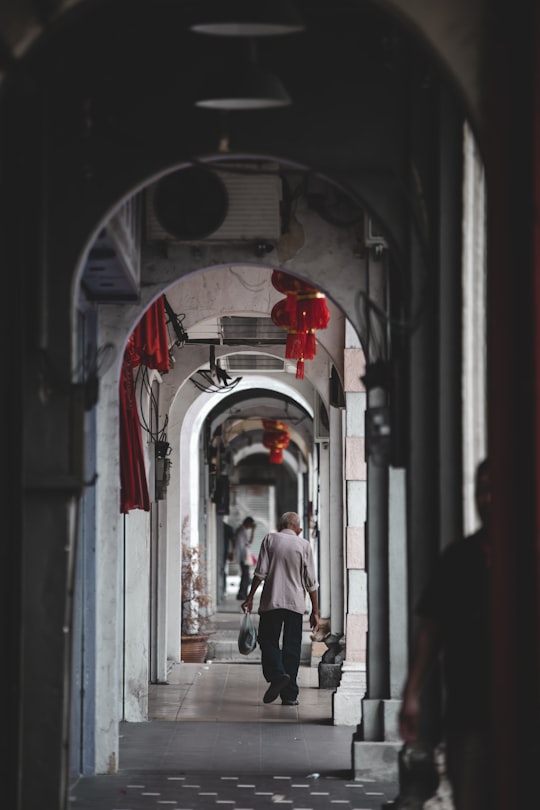 woman in white shirt and black pants walking on hallway in Ipoh Malaysia