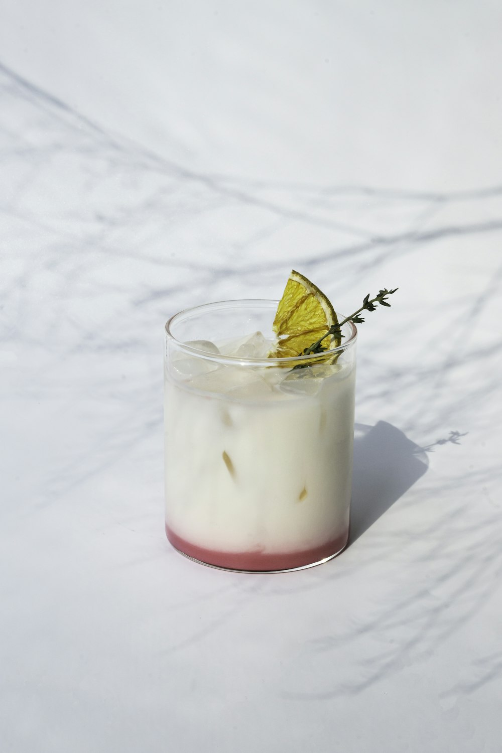 Vaso transparente con líquido rosa y hielo