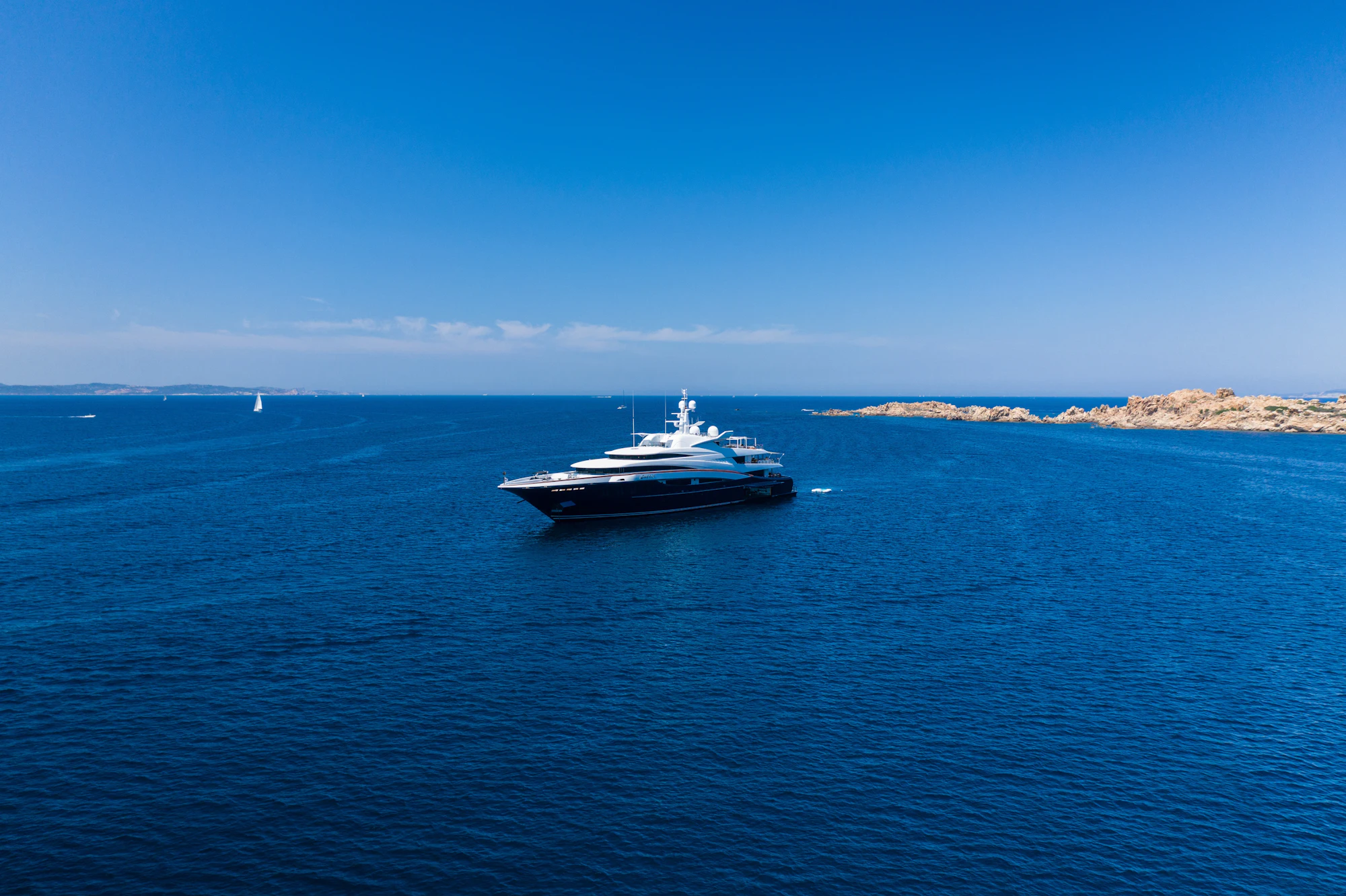 Yacht under way along a rocky coastline