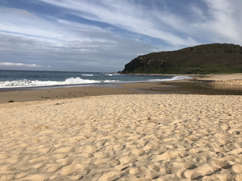 Plage de sable brun avec du sable blanc et une mer bleue sous un ciel bleu pendant la journée