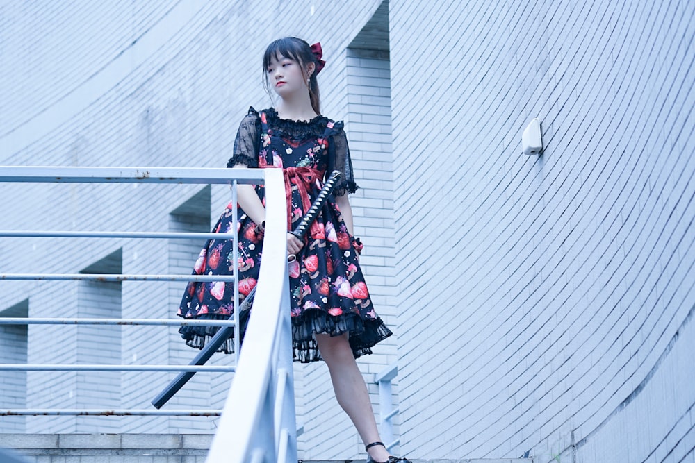 woman in black and red floral dress standing on stairs