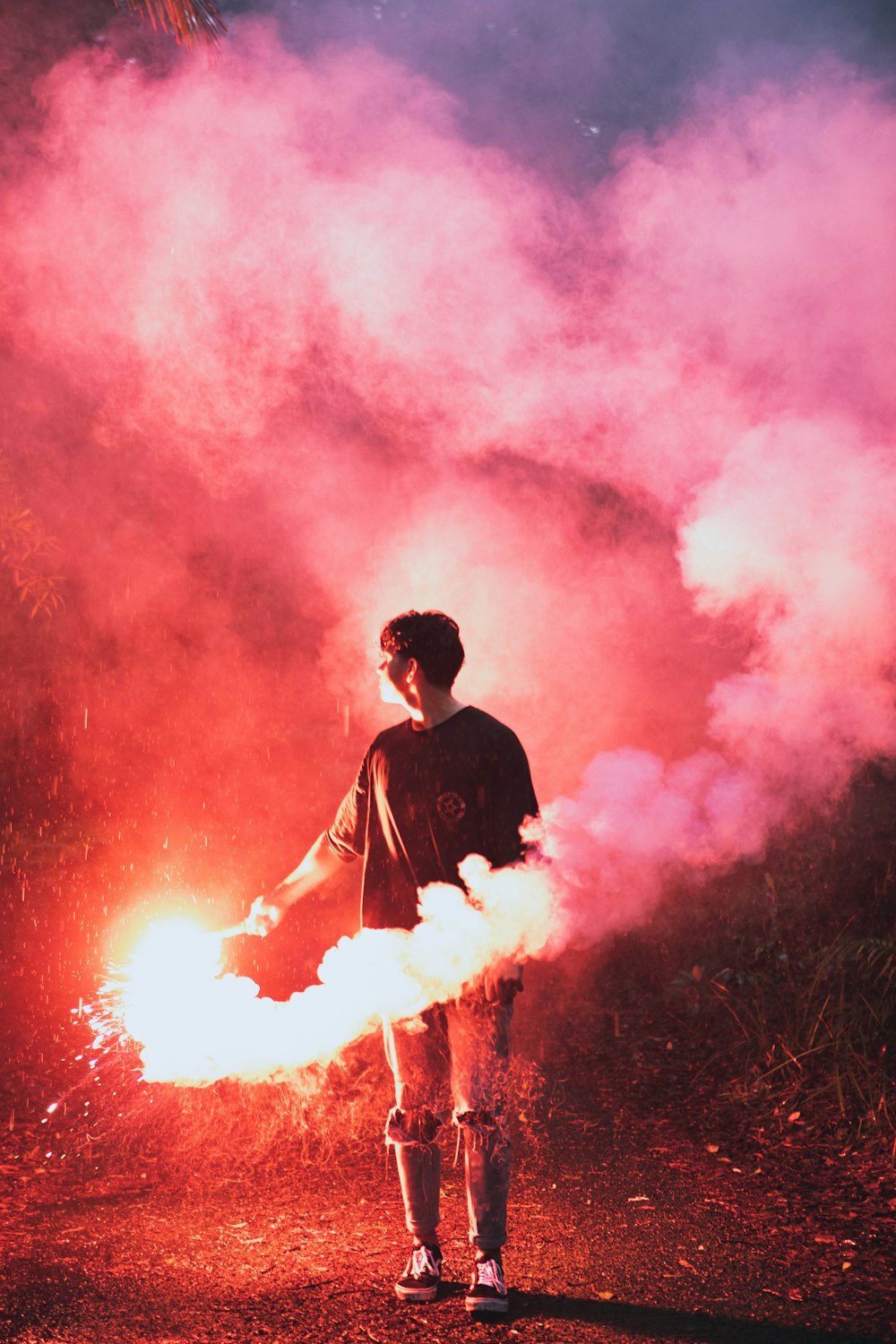 man in black suit standing on red smoke