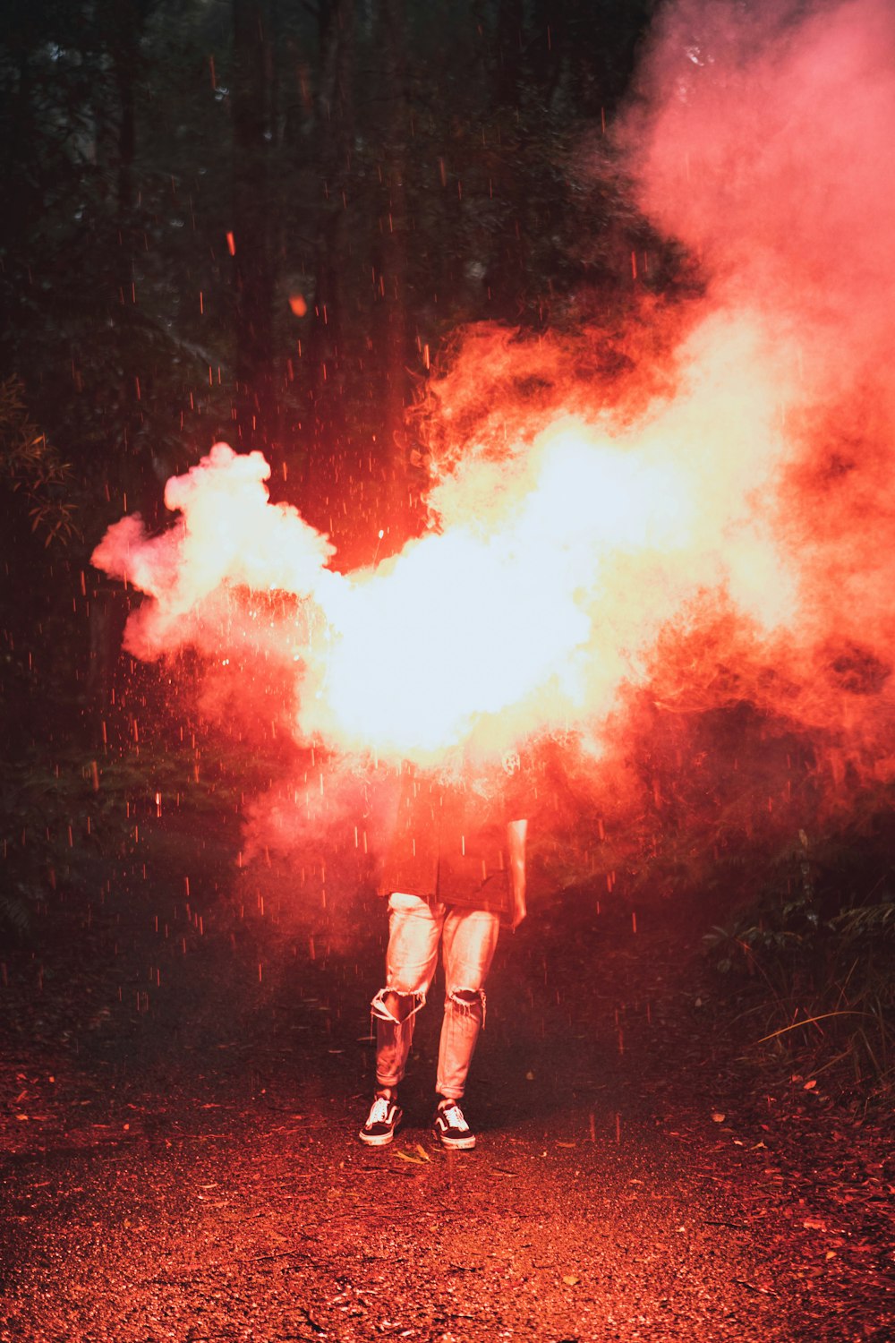 Persona en pantalones cortos blancos de pie sobre humo rojo y blanco