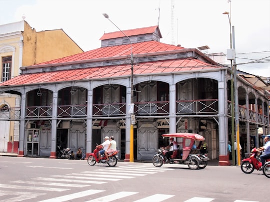 2 men riding motorcycle in front of brown concrete building during daytime in Plaza de Armas Peru