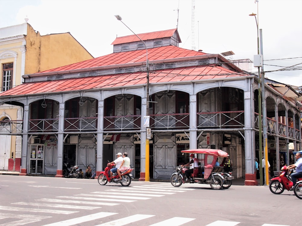 2 men riding motorcycle in front of brown concrete building during daytime