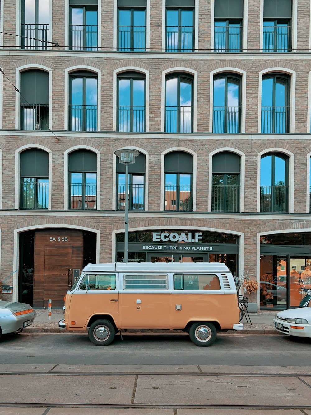 red and white volkswagen t-2 parked in front of brown concrete building during daytime