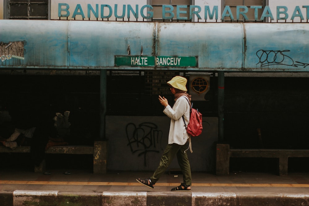 woman in white long sleeve shirt and brown pants wearing brown hat standing near green and