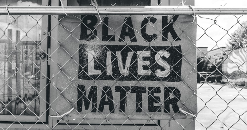 a black lives matter sign on a chain link fence
