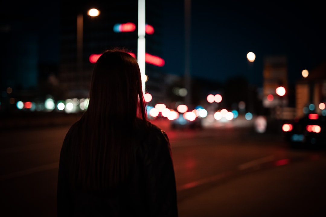 woman in black coat standing on road during night time