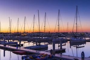 Historic wooden boat gently bobbing on crystal-clear marina waters at sunset.