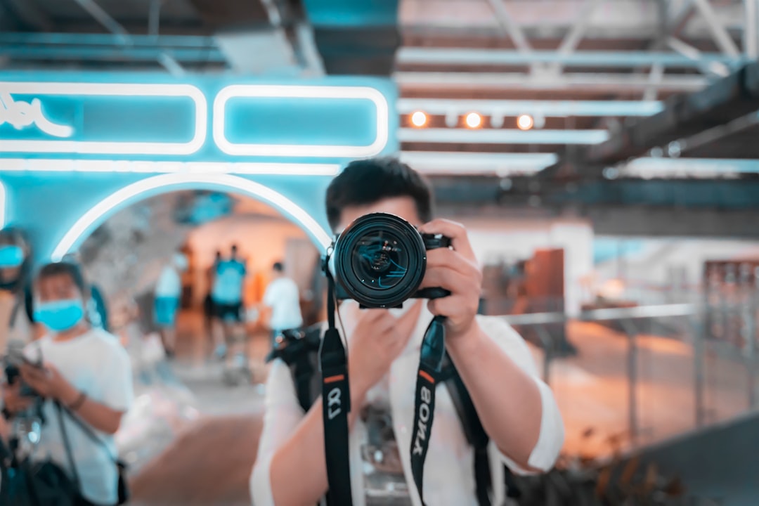 woman in white tank top holding black dslr camera