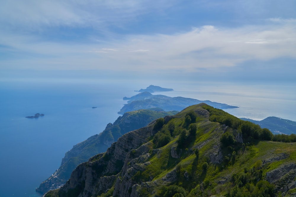 montagna verde accanto al mare blu sotto le nuvole bianche durante il giorno